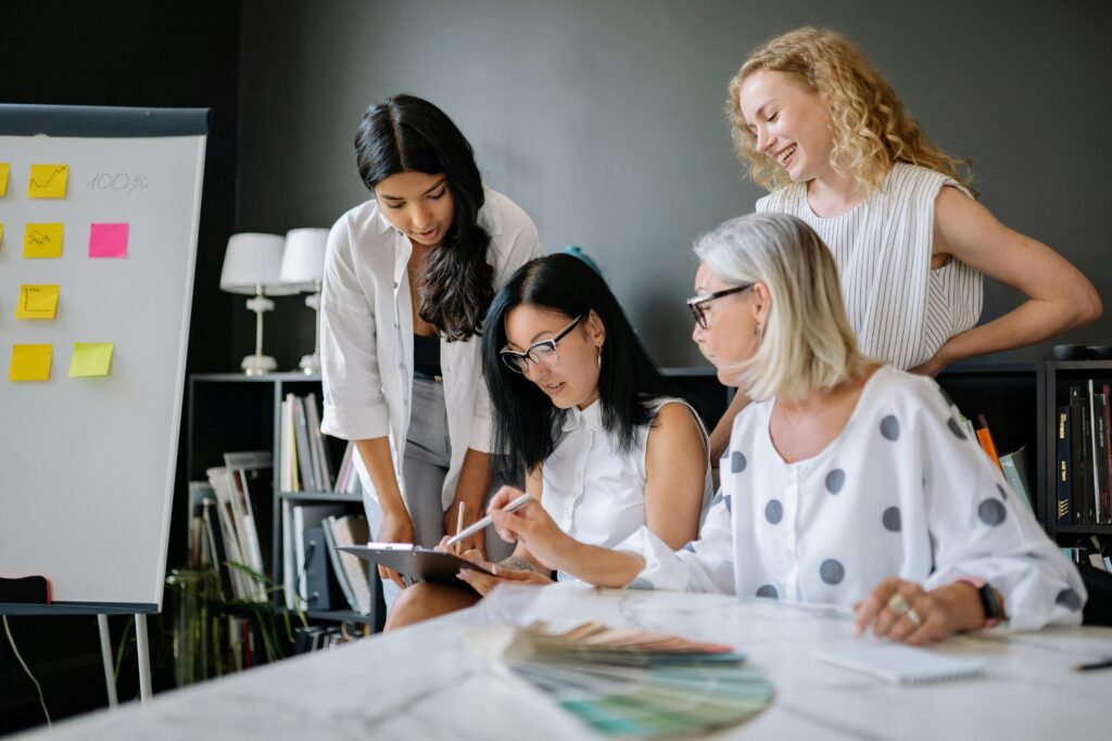 A diverse group of women engaged in a collaborative business meeting in a modern office setting.